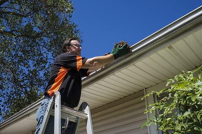 a roofer repairing a damaged gutter on a house in Burlington, VT